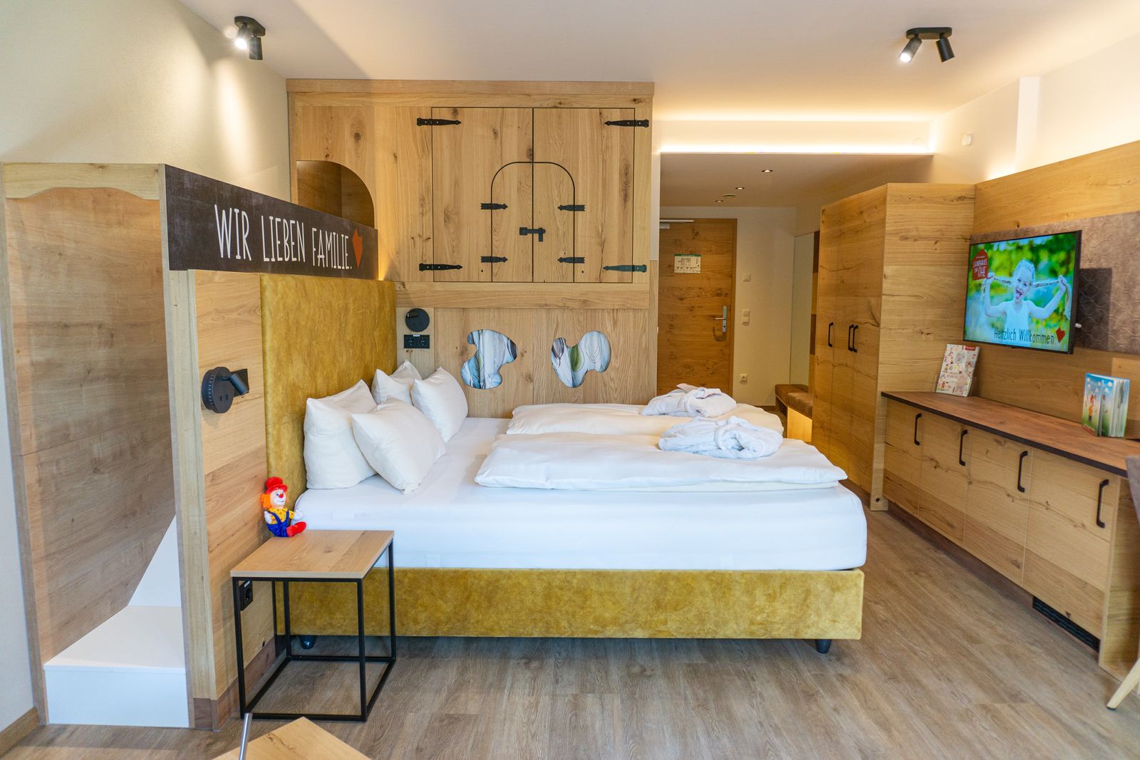 Familienzimmer mit Doppelbett und Rutsche hinter dem Elternbett, eingehaustes Stockbett für die Kinder