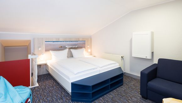 links der Treppenaufgang, daneben das Doppelbett im Kinderzimmer, rechts ein Sofa